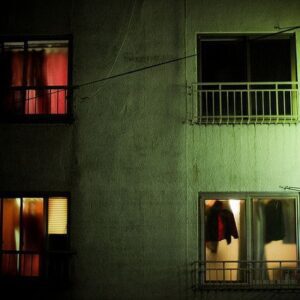 Gece vakti bir apartmanın turuncu ışıkla aydınlanmış pencereleri